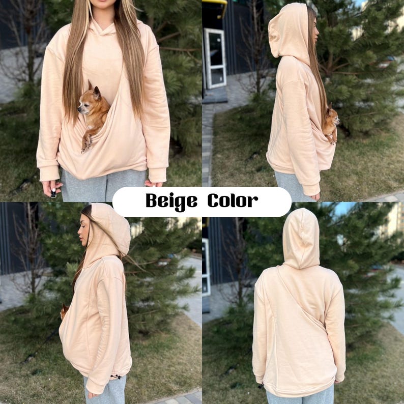 Op de afbeelding: Beige hoodie met een ingebouwde zak voor een kleine hond. De hoodie heeft een capuchon met trekkoord en een kangoeroezak. Het model draagt de hoodie met een kleine hond in de zak.