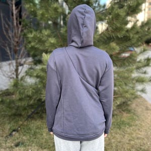 Op de afbeelding: Een donkergrijze hoodie met lange mouwen. De hoodie heeft een diagonale naad op de rug.