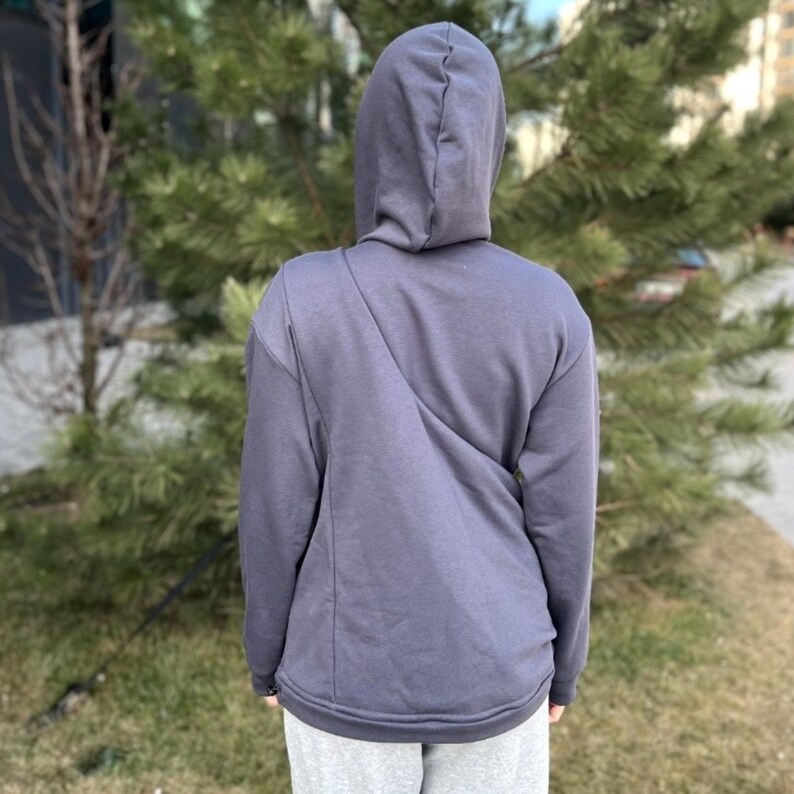 Op de afbeelding: Een donkergrijze hoodie met lange mouwen. De hoodie heeft een diagonale naad op de rug.