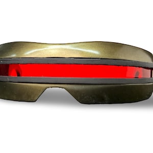 Op de afbeelding: Een zonnebril in vizierstijl met een metallic bronskleurig montuur en een enkel, doorlopend horizontaal rood glas. Het ontwerp bevat een dikke zwarte rubberen rand die de bovenste en onderste delen van het montuur van elkaar scheidt.