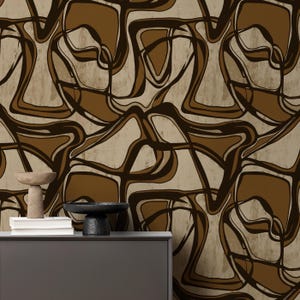 Puede incluir: Papel tapiz abstracto con un patrón marrón y beige de líneas y formas que se arremolinan. El papel tapiz se muestra en una pared detrás de una cómoda gris oscura.