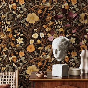 May include: A dark brown wallpaper with a floral pattern featuring intricate vines, leaves, and flowers in shades of yellow, orange, and cream. The wallpaper is displayed in a room with a wooden dresser and a bust of a woman.