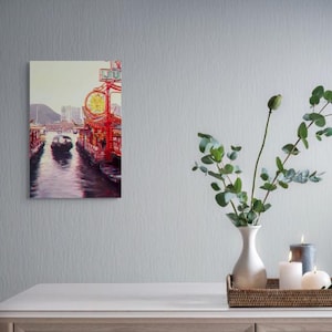 Könnte beinhalten: Ein Leinwanddruck einer Wasserwegszene mit traditionellen roten und goldenen Strukturen. Ein schwarzes Boot befindet sich im Wasser. Der Druck wird auf einem weißen Tisch mit einer Vase mit Grün, Kerzen und einem dekorativen Tablett ausgestellt.