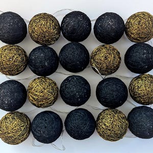 May include: A string of 20 cotton ball lights with a mix of black and gold colors. The lights are arranged in a grid pattern.