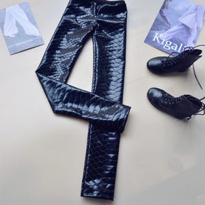 Op de afbeelding: Zwarte leggings van imitatieleer met een slangenhuidpatroon.