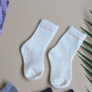 May include: Two pairs of white ankle socks. The socks are made of a soft, knitted fabric.