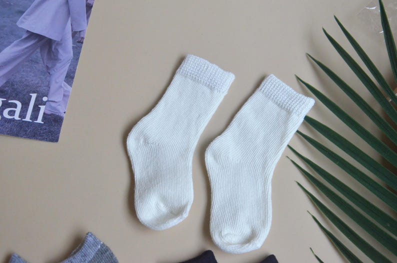 May include: Two pairs of white ankle socks. The socks are made of a soft, knitted fabric.