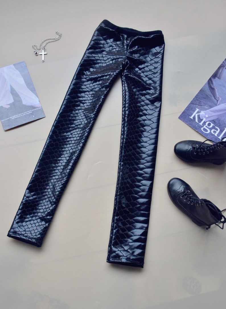 May include: Black faux leather leggings with a snakeskin pattern.