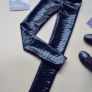 May include: Black faux leather leggings with a snakeskin pattern.