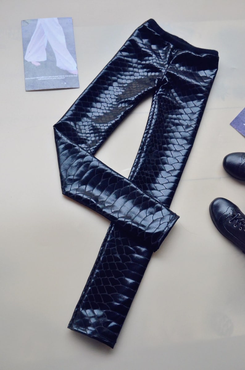 May include: Black faux leather leggings with a snakeskin pattern.