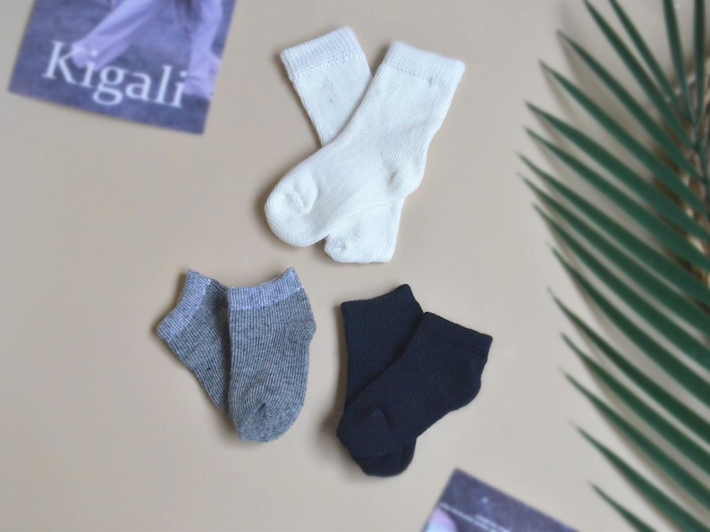 May include: Three pairs of socks in different colours: white, grey, and black. The socks are all ankle-length and made of a soft, comfortable material.