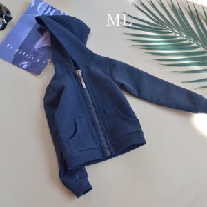 Könnte beinhalten: Ein marineblauer Kapuzenpullover mit Reißverschluss und einer Tasche auf der Vorderseite. Der Pullover ist aus einem weichen, bequemen Stoff.