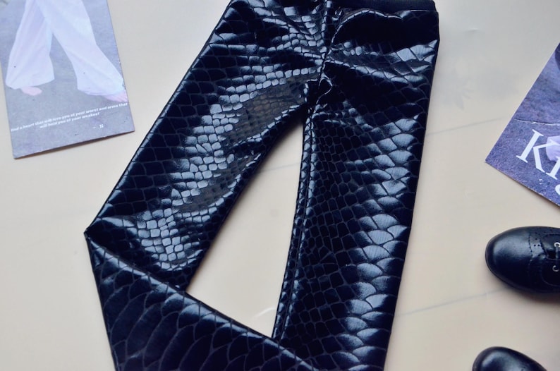 May include: Black faux leather trousers with a snakeskin pattern.