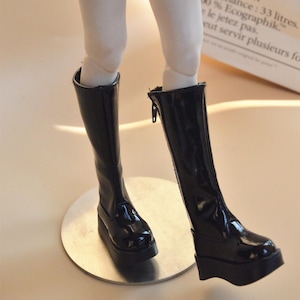 May include: A pair of black knee-high boots with a shiny finish and a thick platform sole.