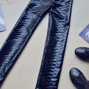 May include: Black faux leather leggings with a snakeskin pattern.