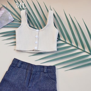 May include: A white ribbed tank top with a button closure and a pair of dark blue denim shorts.