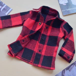 May include: Red and black plaid flannel shirt with long sleeves and button closure.