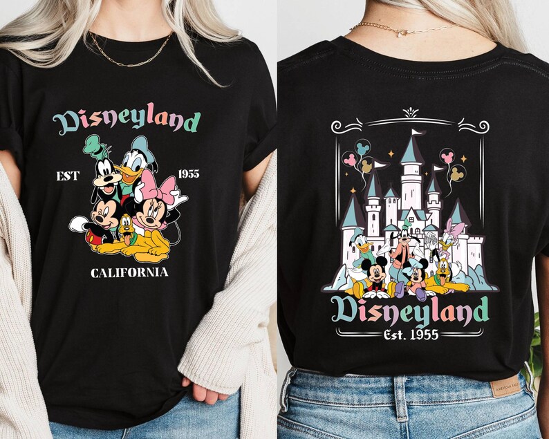 May include: Black t-shirt with a colorful Disneyland graphic featuring Mickey Mouse, Minnie Mouse, Donald Duck, Goofy, and Pluto. The graphic includes the text "Disneyland Est. 1955 California". The back of the shirt features a colorful graphic of Sleeping Beauty's castle with the text "Disneyland Est. 1955".