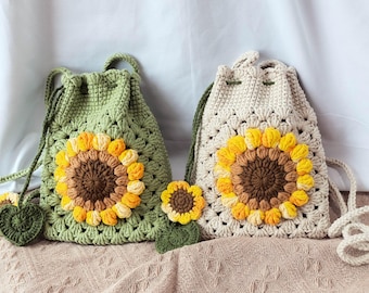 Puede incluir: Dos bolsas de crochet con diseños de girasoles. Una bolsa es verde y la otra es beige.