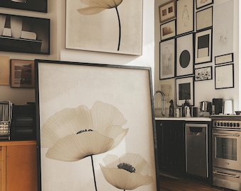 Pode incluir: Grandes impressões de arte emolduradas com delicadas ilustrações de flores de papoula translúcidas em tons suaves de bege e creme. A obra de arte é definida em um fundo neutro, com caules pretos e uma moldura preta. A imagem é exibida em uma sala bem iluminada com outras obras de arte emolduradas.