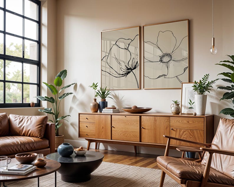 May include: A living room scene featuring a mid-century modern aesthetic. Two large framed floral art prints hang above a wooden sideboard. The room includes leather furniture, plants, and decorative items, creating a warm and inviting atmosphere.