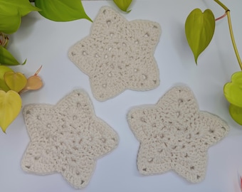 May include: Three white crocheted star-shaped coasters. The coasters are made of a soft, textured yarn and have a delicate, lacy design.