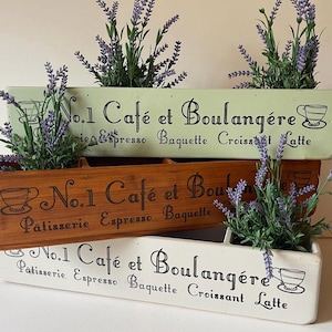 May include: Three rectangular wooden planter boxes in light green, natural brown, and white. Each box features the black text No.1 Café et Boulangère, Patisserie, Espresso, Baguette, Croissant, Latte, and cup icons. Artificial lavender sprigs are inside.