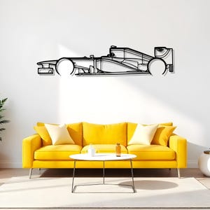 May include: Black metal wall art depicting a Formula 1 race car. The artwork is a minimalist outline of the vehicle, mounted on a white wall above a yellow sofa. The car's wheels and body are clearly defined.