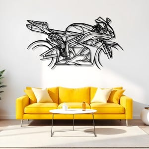 May include: A black metal motorcycle wall art piece. The artwork depicts a detailed outline of a sport bike, mounted on a white wall above a yellow sofa. The motorcycle design features intricate lines and shapes.