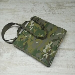 May include: A camouflage-patterned tote bag with a top handle and adjustable shoulder strap. The bag has a flap closure with a buckle.