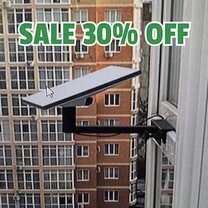 May include: A black solar panel mounted on a bracket, attached to a window frame. The panel has a white top surface. The text "SALE 30% OFF" is displayed in green above the panel. The background shows a multi-story building.