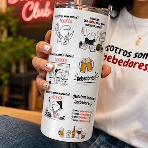 Może przedstawiać: Biały kubek ze stali nierdzewnej z pokrywką i słomką. Kubek zawiera humorystyczne ilustracje z kreskówek i tekst w języku hiszpańskim, w tym frazę "Bebedores Club". Projekt zawiera obrazy kufli do piwa i kieliszków do wina.