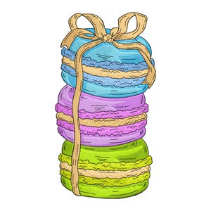 Op de afbeelding: Geborduurd beeld van drie macarons in een stapel, in blauwe, paarse en groene tinten, vastgebonden met een beige lint. De macarons hebben een textuur, met een lichtgele vulling zichtbaar tussen de lagen. De achtergrond is wit.