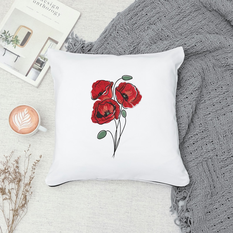 May include: White square throw pillow featuring a red poppy floral design. The pillow has a black trim and a soft, textured appearance. The poppy flowers are detailed with red petals and green stems.