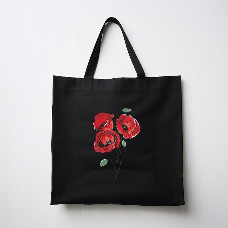 May include: Black tote bag featuring a red poppy flower design. The illustration shows three red poppies with green leaves and thin black stems. The tote bag has black handles and is made of a durable fabric.