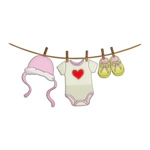 May include: A pink baby hat with ear flaps, a light green onesie with a red heart, and yellow baby shoes with pink bows hang from a clothesline. The items are secured with wooden clothespins, suggesting a baby-themed design.