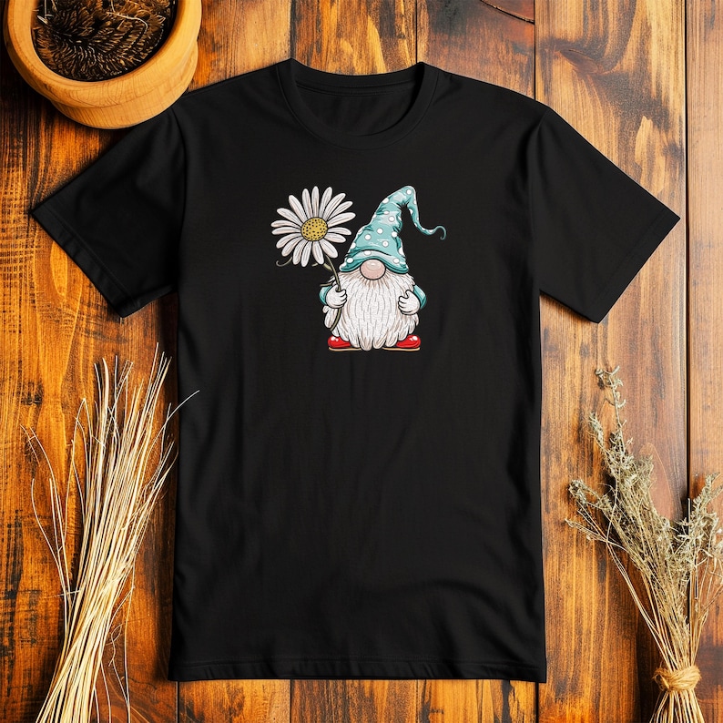 May include: Black t-shirt with a white daisy and a blue gnome holding the flower. The gnome is wearing a blue hat with white polka dots and red shoes.