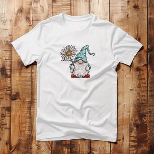 May include: White t-shirt with a cartoon gnome holding a daisy. The gnome is wearing a blue and white polka dot hat and red shoes.