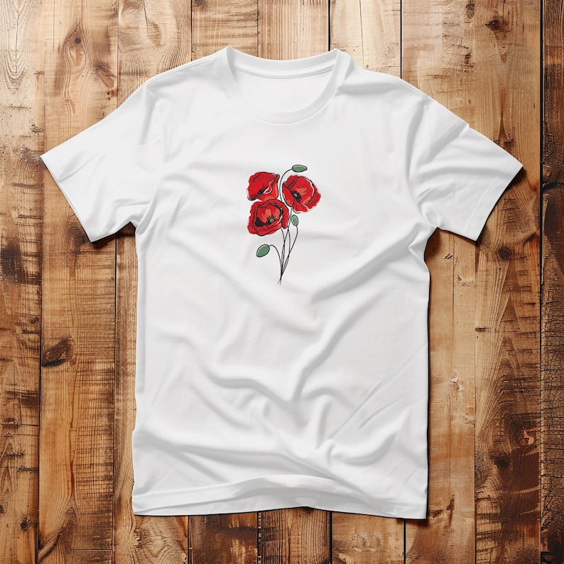 May include: White t-shirt featuring a detailed illustration of three red poppies with green stems and leaves. The floral design is centered on the chest. The shirt is made of a soft, lightweight fabric.