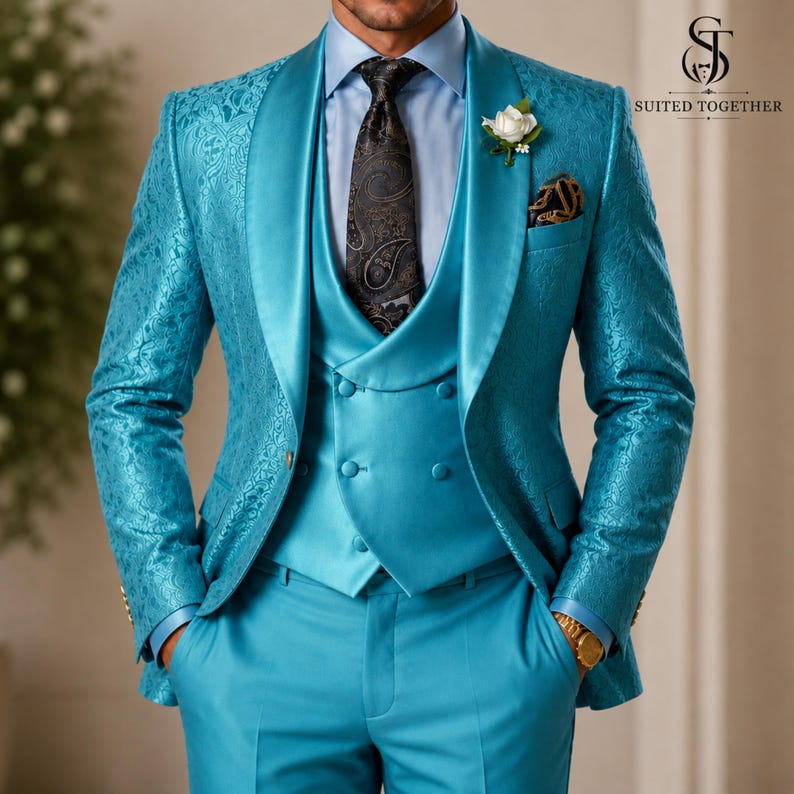 May include: A bright turquoise suit featuring a patterned blazer with a shawl lapel, a double-breasted waistcoat, and matching trousers. The ensemble includes a light blue dress shirt, a dark patterned necktie, and a white floral lapel pin.
