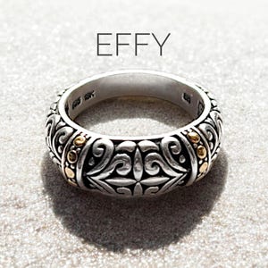 May include: A silver ring with a gold band and intricate design. The ring is engraved with the word "EFFY".
