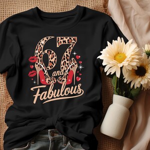 May include: Black t-shirt with a leopard print number 67 and the words "and fabulous" printed on it. The number 67 is decorated with two leopard print high heels.