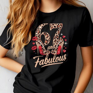 May include: Black t-shirt with a leopard print design featuring the number 67 and the words "and fabulous" in gold lettering. Two red high heels are shown on either side of the number.