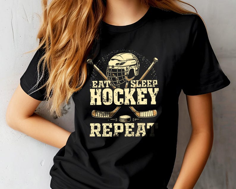 May include: Black t-shirt featuring a hockey stick and helmet graphic. The text on the shirt reads "Eat Sleep Hockey Repeat."