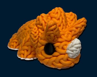 May include: A 3D-printed orange fox figurine with a brain-like texture. The fox has a black eye and a white patch on its face. The figurine is set against a dark blue background.