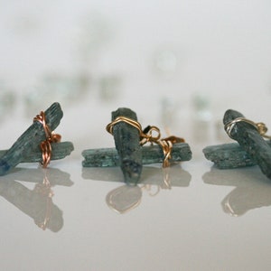 May include: Three pairs of earrings featuring blue kyanite crystals wrapped in copper and gold wire.