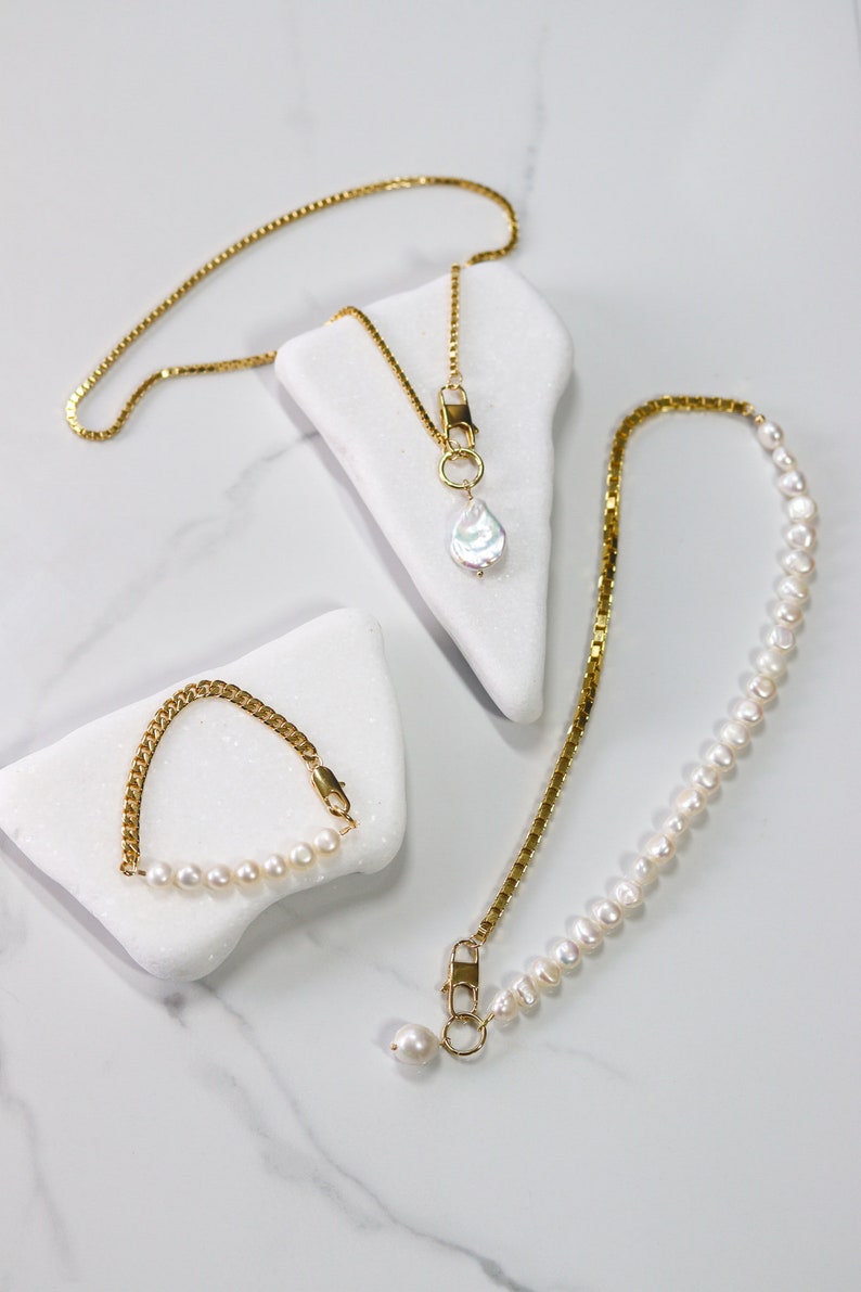 May include: Three gold necklaces with pearl accents. One necklace features a single large pearl pendant, another has a row of smaller pearls, and the third is a simple chain with a small pearl pendant.