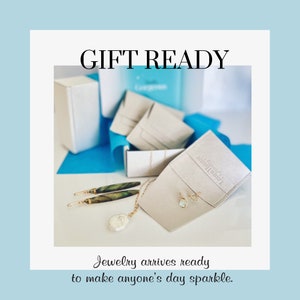 May include: Gift ready jewelry packaging with a necklace, earrings, and a pair of earrings in a white pouch with the text "Love & Jewelry" on it. The jewelry is on a white surface with a blue background.