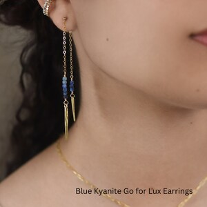 May include: Gold earrings with a blue kyanite stone and a long chain. The earrings are called "Blue Kyanite Go for Lux Earrings".