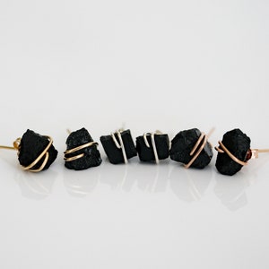May include: A set of six black stone earrings with gold and silver wire accents. The earrings are all different shapes and sizes.
